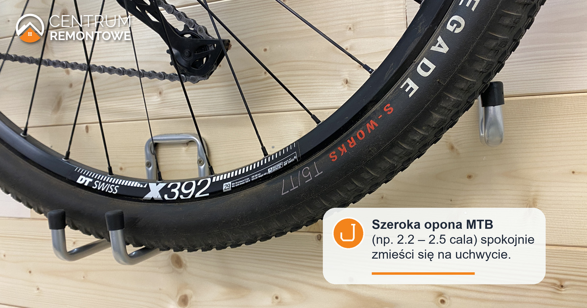 Szeroka opona roweru górskiego 29 cali na tylnej części uchwytu na rower umieszczonego na drewnianej ściance w domu