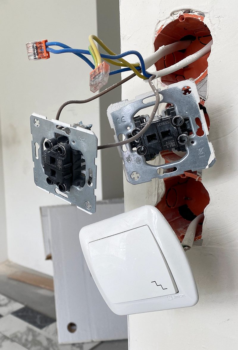 Montaż łączników oświetlenia w trakcie - zbliżenie na 3 elementy będące częścią domowej instalacji elektrycznej.