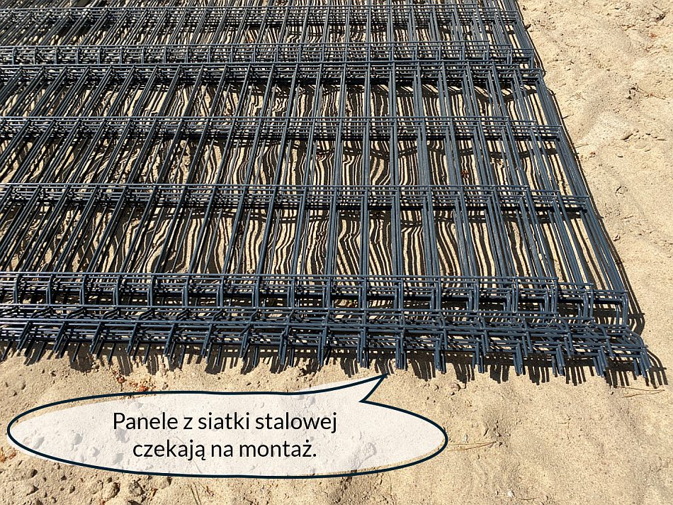 Panele służące do zmontowania ogrodzenia z siatki stalowej - złożone na ziemi czekają na zamontowanie.