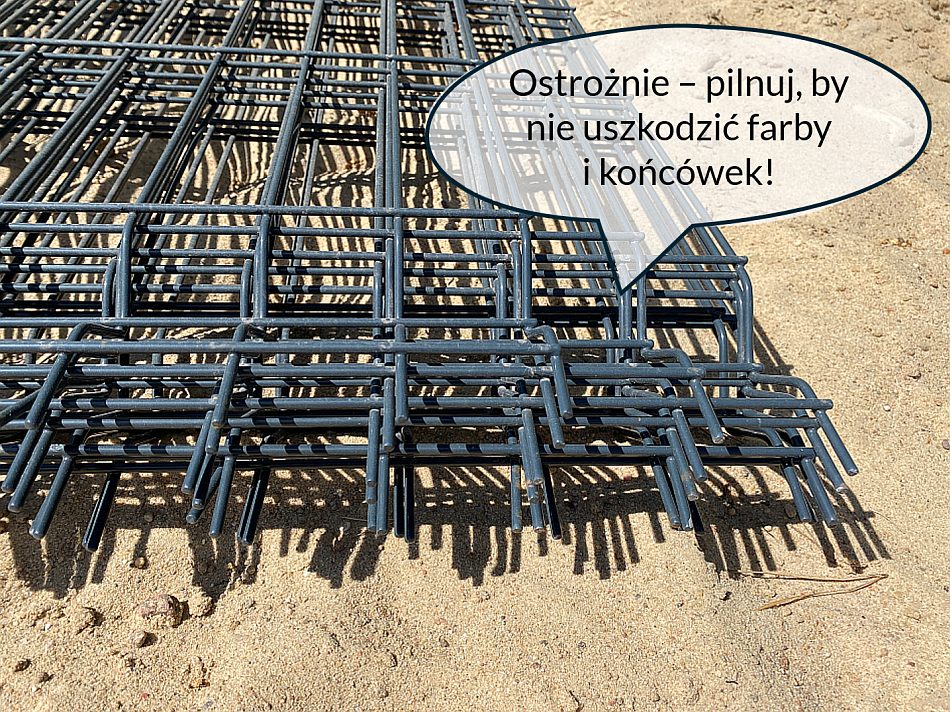 Panele służące do zmontowania ogrodzenia z siatki stalowej - złożone na ziemi czekają na zamontowanie.